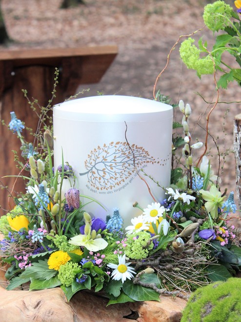 Weiße Urne von Blumen umrahmt mit Blatt als Verzierung