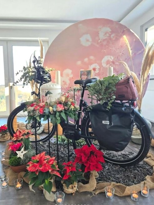 Schwarzes Fahrrad umgeben von Blumen für Trauerfeier